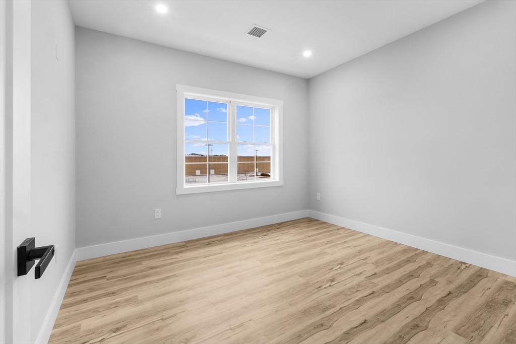 889-895 Grinnell Street, Unit 2 Fall River, MA 02721 - Photo 22 of 42 an empty room with wooden floor and windows