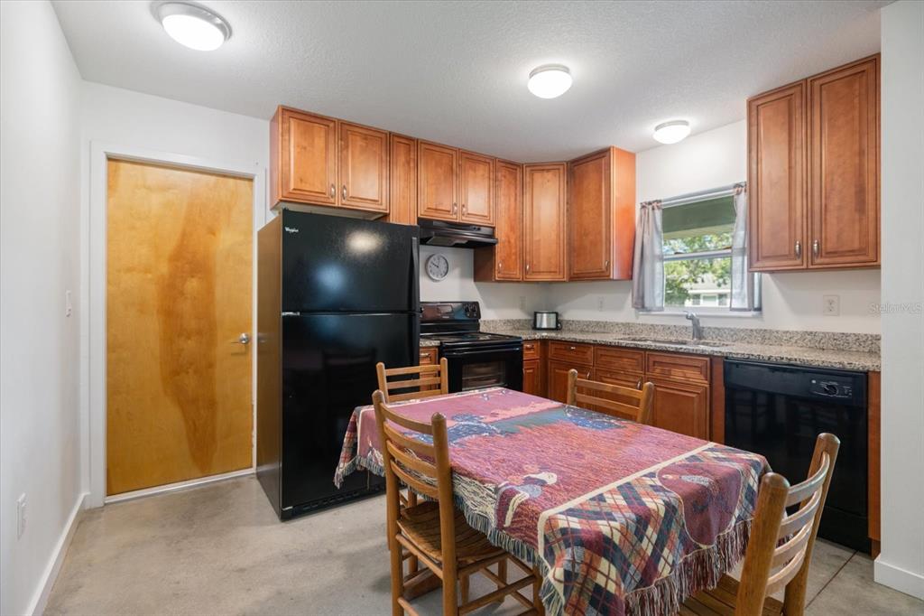 8915 Vamo Road Sarasota, FL 34231 - Photo 28 of 61 a kitchen with a chandelier a refrigerator and wooden cabinets