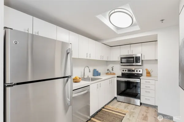 a kitchen with stainless steel appliances a refrigerator sink and white cabinets