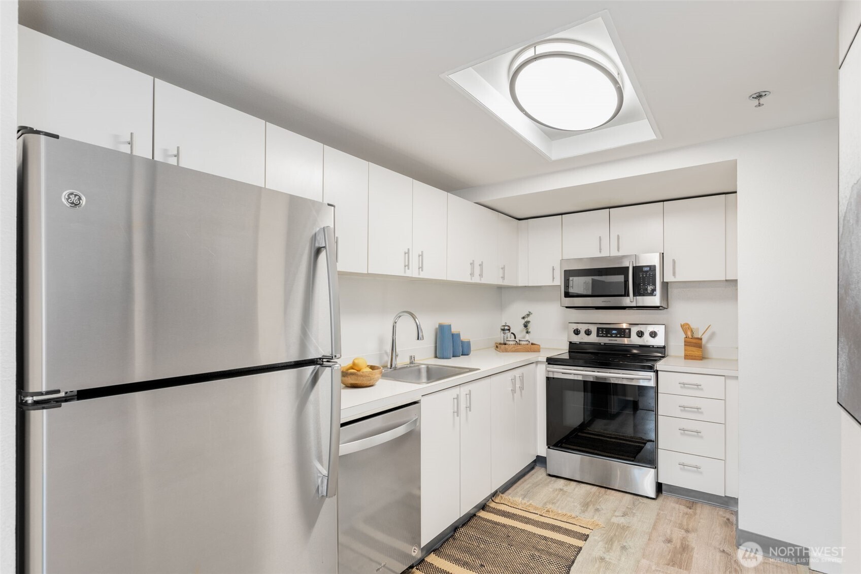 121 Vine Street, Unit 1507 Seattle, WA 98121 - Photo 11 of 40 a kitchen with stainless steel appliances a refrigerator sink and white cabinets