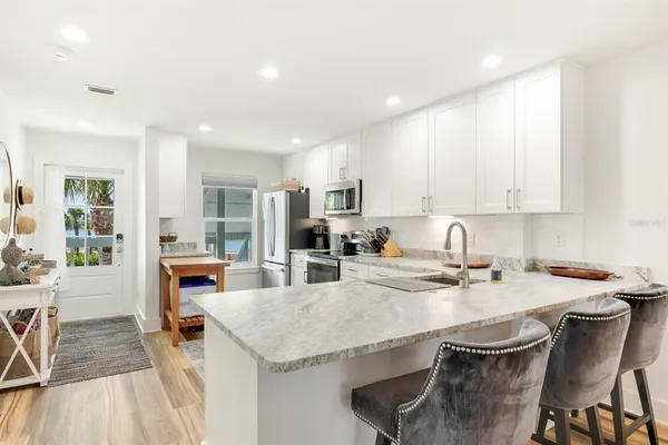 a kitchen with stainless steel appliances granite countertop a table chairs sink refrigerator and cabinets