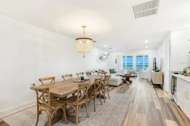 a view of a dining room and livingroom with furniture wooden floor a rug and a chandelier