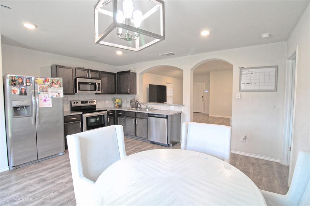 2428 Rosharon Drive Forney, TX 75126 - Photo 23 of 34 a kitchen with stainless steel appliances kitchen island granite countertop a refrigerator a stove top oven a sink dishwasher and white cabinets with wooden floor