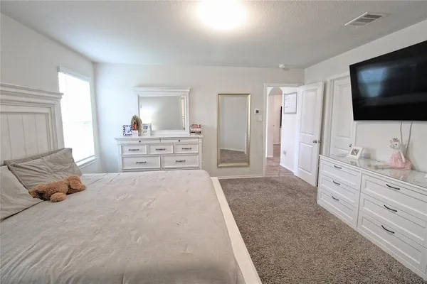 a large bedroom with a bed and flat screen tv