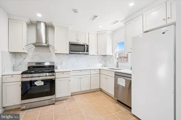 a kitchen with stainless steel appliances granite countertop a stove a sink and a refrigerator