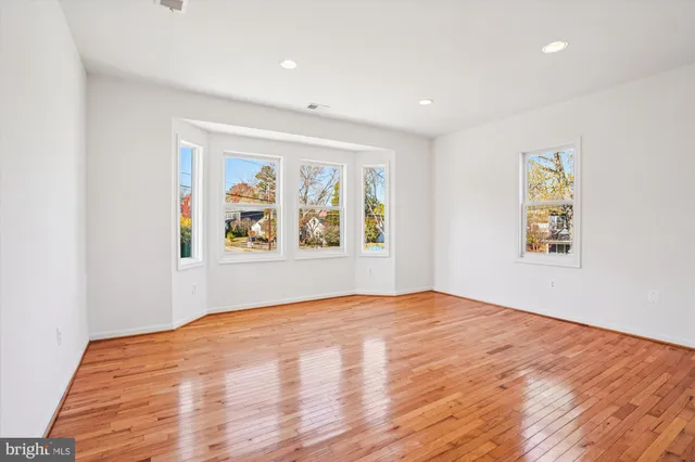 a view of an empty room with window and wooden floor