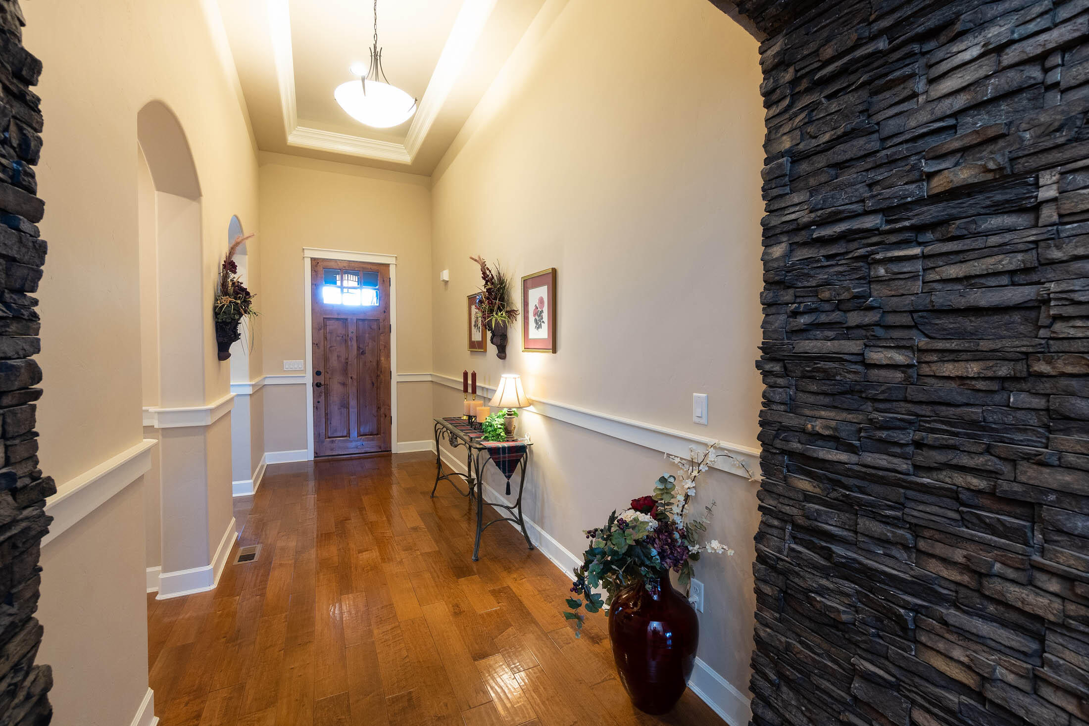 61129 Manhae Loop Bend, OR 97702 - Photo 3 of 44 Entry view: Upgraded stone masonry wrapped entry to the open greatroom. Upgraded, tall, solid wood door with transom windows. Tall, coffered ceiling with crown molding, lower chair rail molding, and beautiful arched doorways.