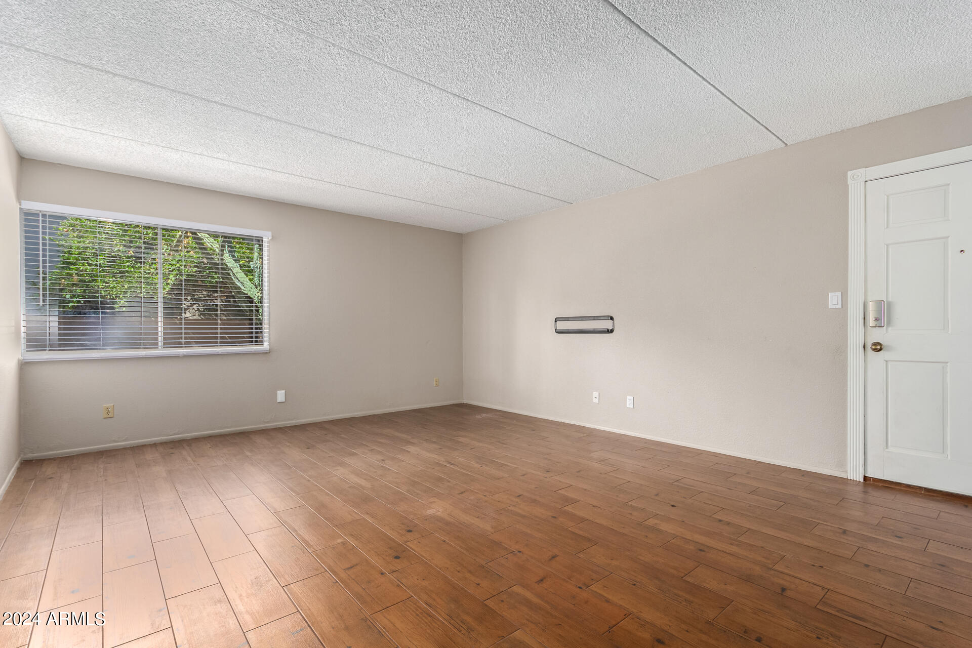 4201 East Camelback Road, Unit 35 Phoenix, AZ 85018 - Photo 13 of 33 an empty room with wooden floor and windows