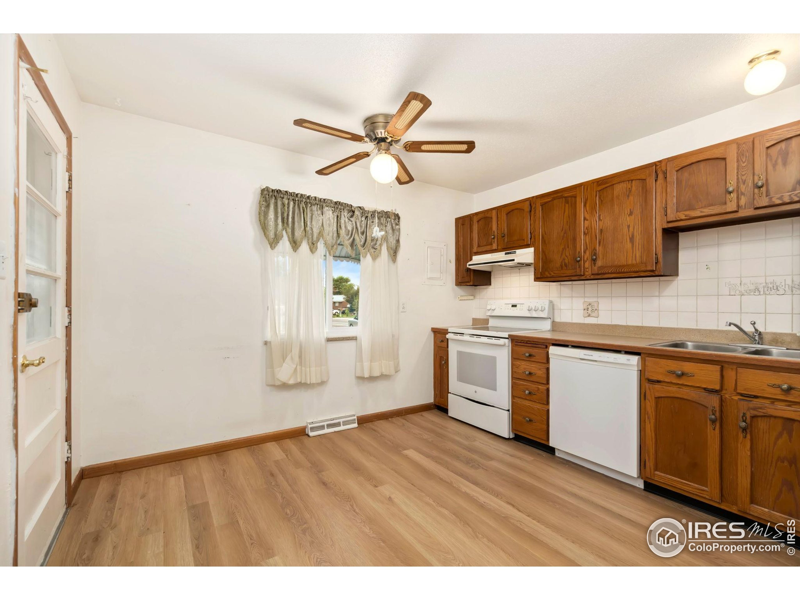 2046 26th Street Road Greeley, CO 80631 - Photo 11 of 34 a kitchen with stainless steel appliances granite countertop a sink cabinets and wooden floor