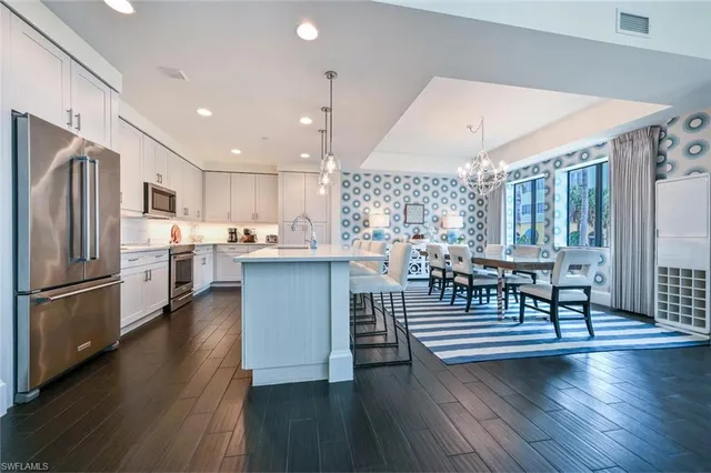 a kitchen with stainless steel appliances granite countertop a refrigerator a stove a sink dishwasher a dining table and chairs with wooden floor