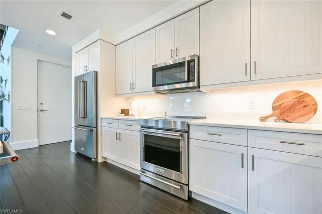 a kitchen with stainless steel appliances white cabinets and a refrigerator