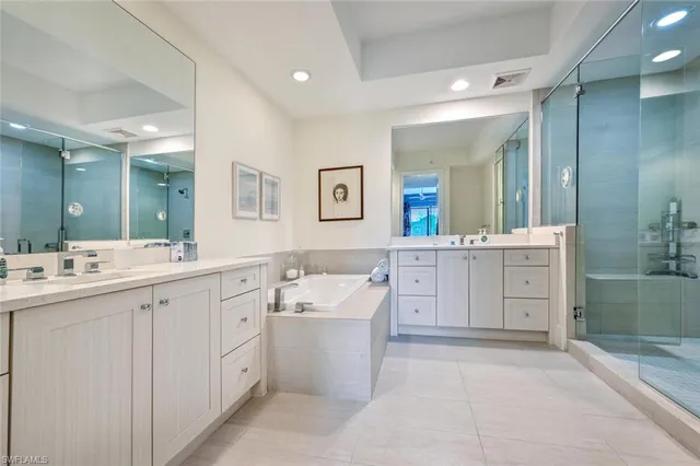 a spacious bathroom with a double vanity sink mirror and bathtub