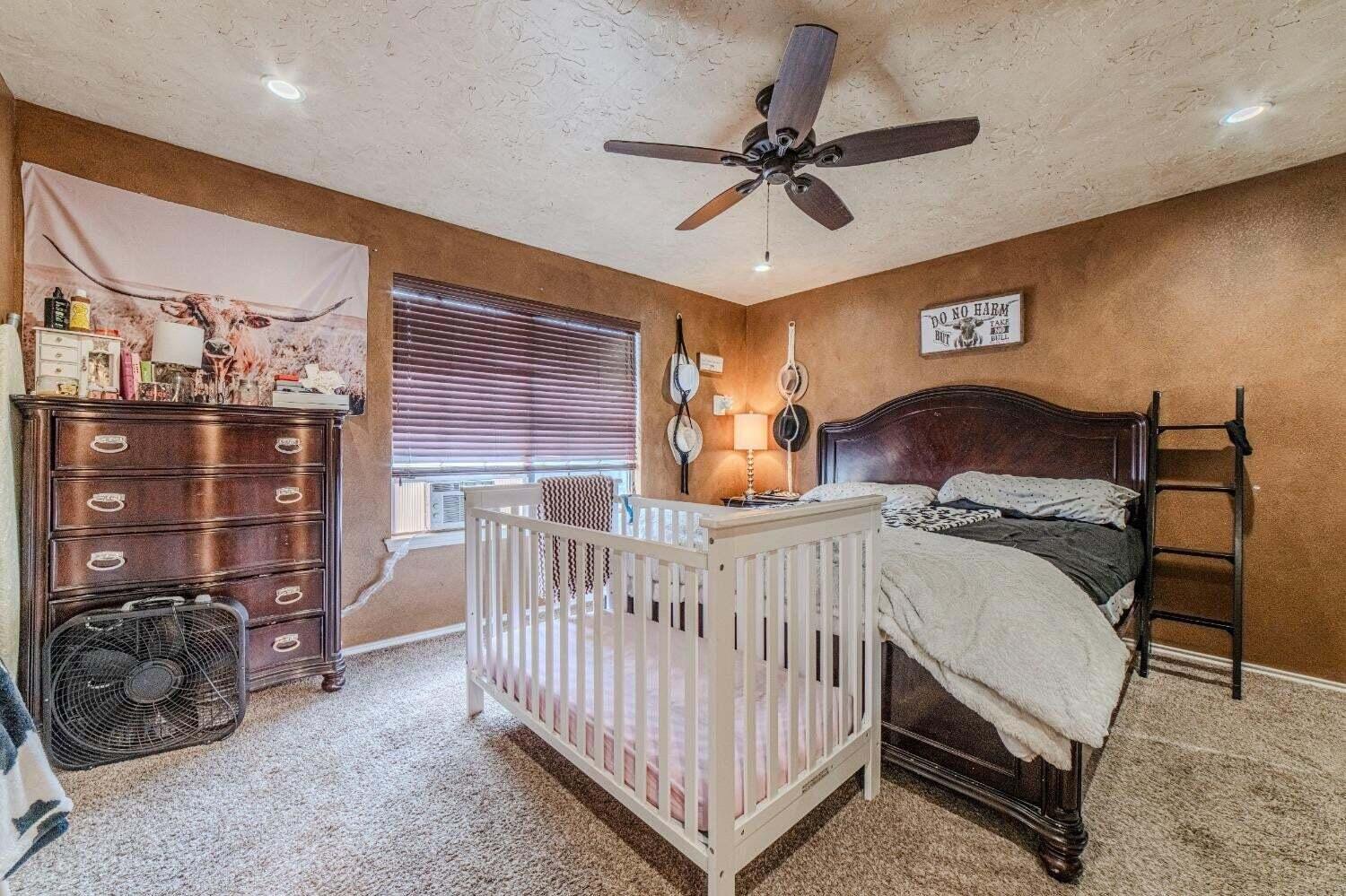 6015 14th Street Lubbock, TX 79416 - Photo 12 of 24 a bedroom with a bed a chandelier and dresser
