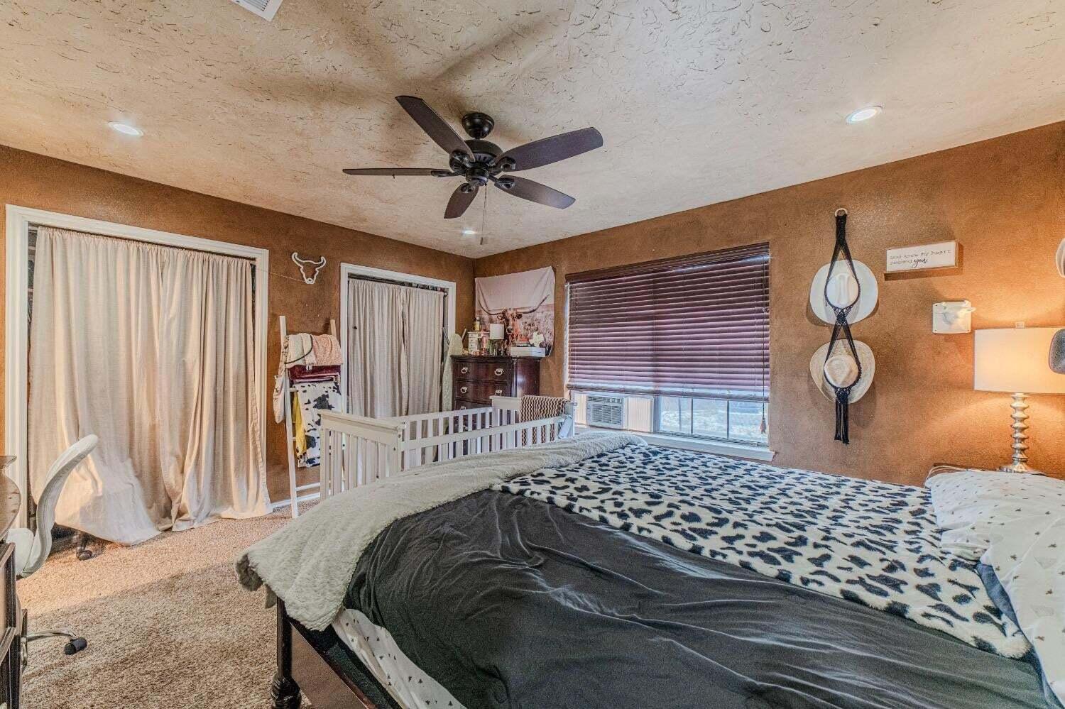 6015 14th Street Lubbock, TX 79416 - Photo 13 of 24 a bedroom with a bed and dresser with wooden floor