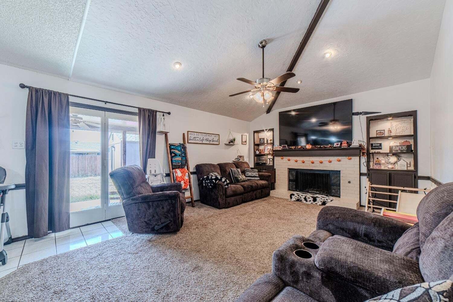 6015 14th Street Lubbock, TX 79416 - Photo 6 of 24 a living room with furniture a flat screen tv and a fireplace