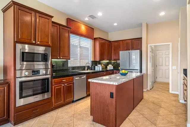 a kitchen with stainless steel appliances granite countertop a refrigerator and a sink