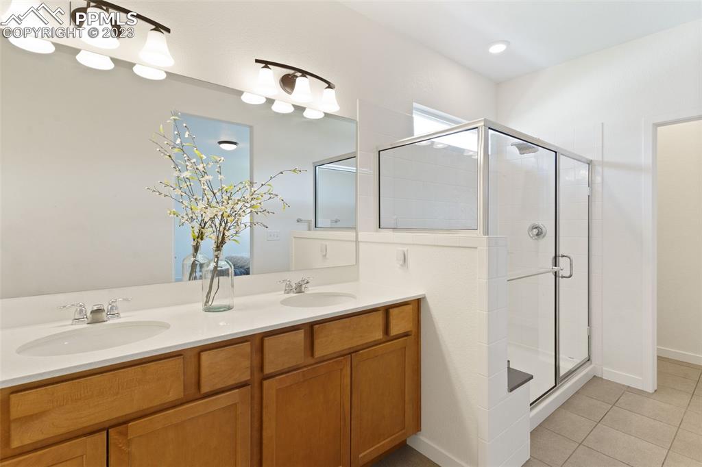 11969 Alydar Loop Colorado Springs, CO 80921 - Photo 18 of 39 a bathroom with a double vanity sink mirror and shower