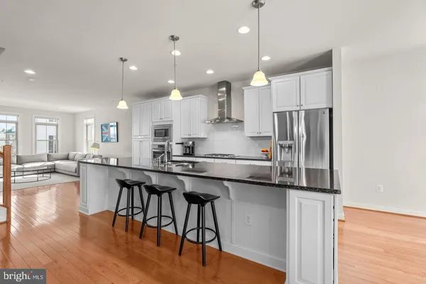 a kitchen with stainless steel appliances granite countertop a refrigerator a sink dishwasher a stove and white cabinets with wooden floor
