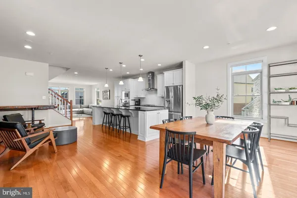 a dining room with stainless steel appliances kitchen island granite countertop a dining table chairs and white cabinets