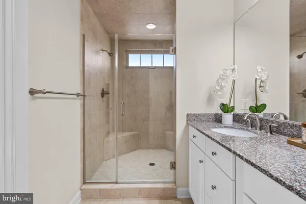 a bathroom with a granite countertop sink a mirror and a shower