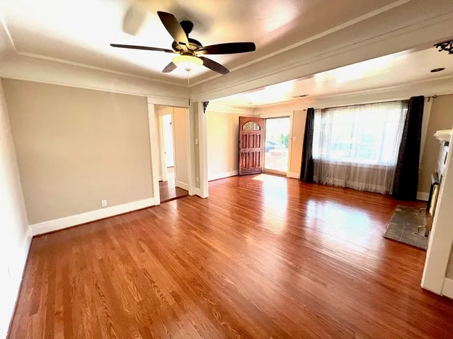 a view of an empty room with window and wooden floor