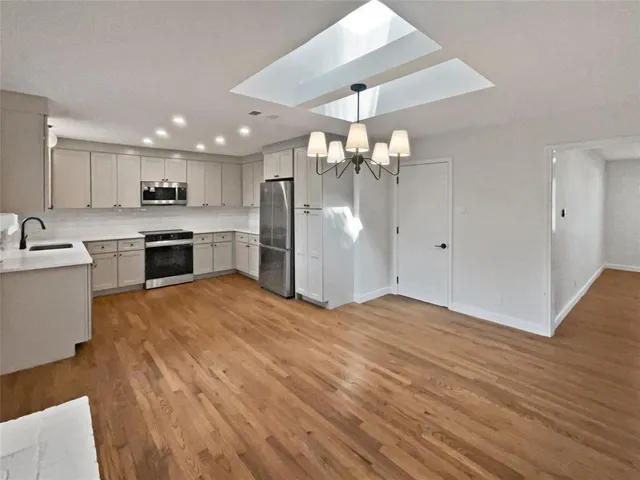 a view of a kitchen with a sink and dishwasher a refrigerator with wooden floor