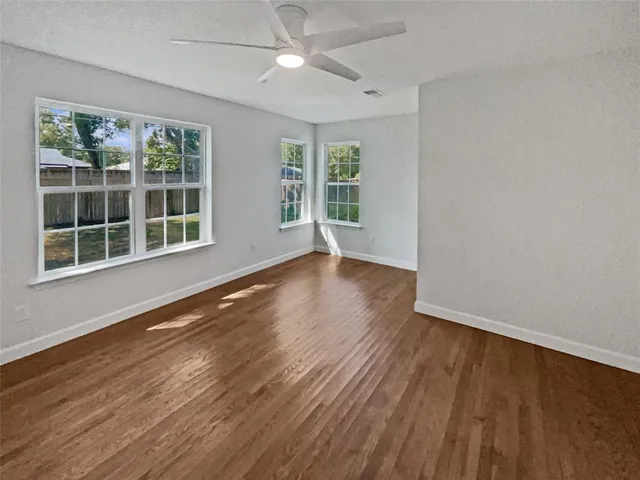 a view of an empty room with wooden floor and a window