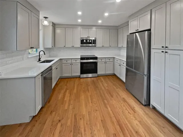 a kitchen with wooden floors stainless steel appliances and white cabinets