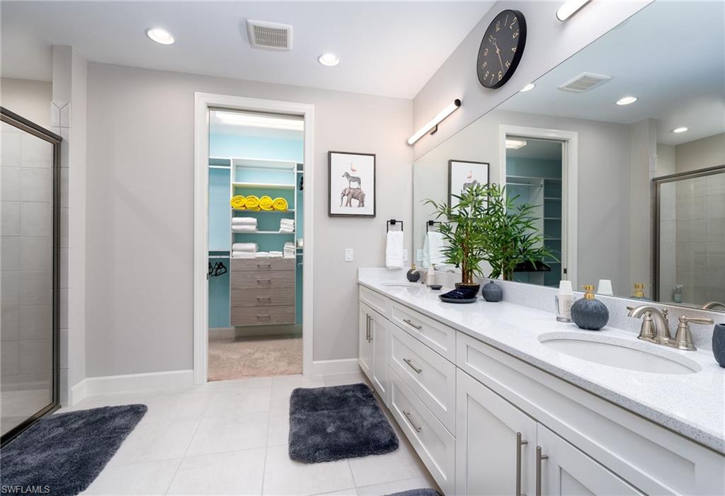 9650 Montelanico Loop, Unit 102 Naples, FL 34119 - Photo 15 of 36 a bathroom with a double vanity sink and a mirror