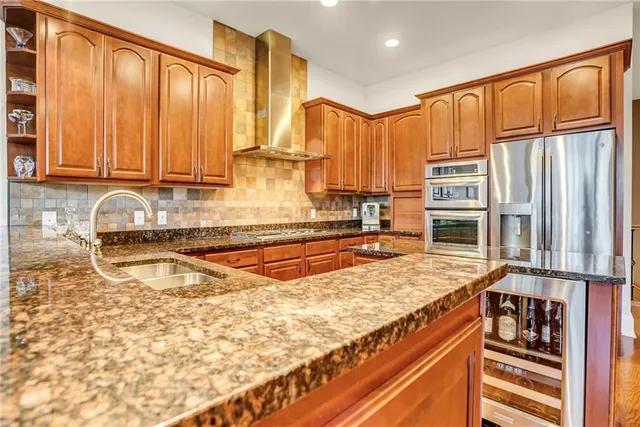 a kitchen with stainless steel appliances granite countertop a sink a stove and a refrigerator