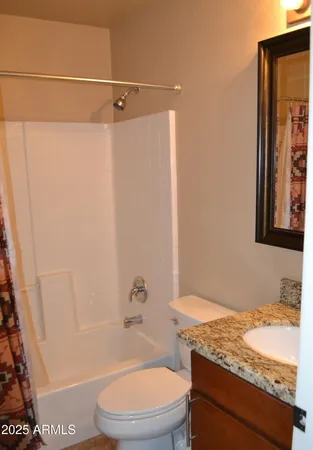 a bathroom with a granite countertop bathtub shower sink vanity and toilet