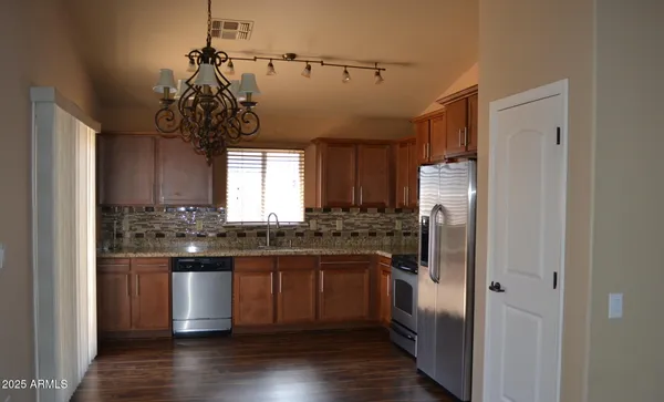 a kitchen with stainless steel appliances granite countertop a refrigerator a sink dishwasher a stove and white cabinets with wooden floor