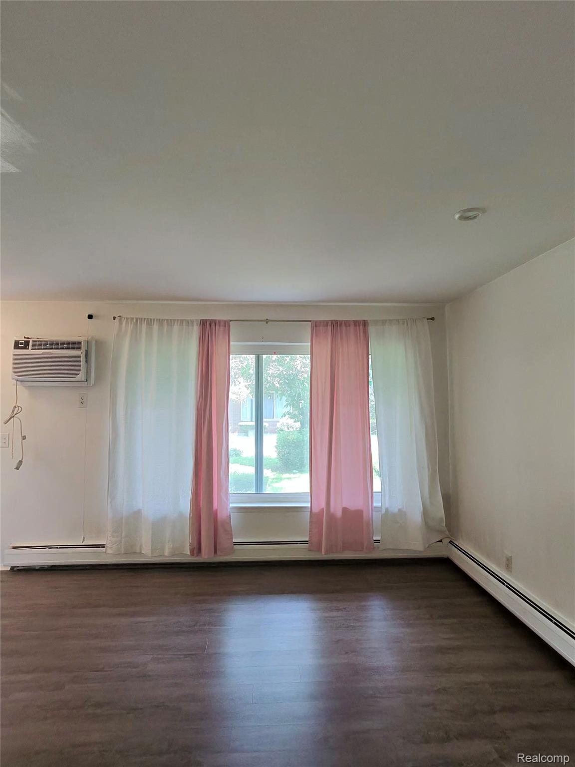 25301 Five Mile Road, Unit 130 Redford, MI 48239 - Photo 4 of 15 Living area featuring wood-finish flooring, a window unit air conditioner, and baseboard heating