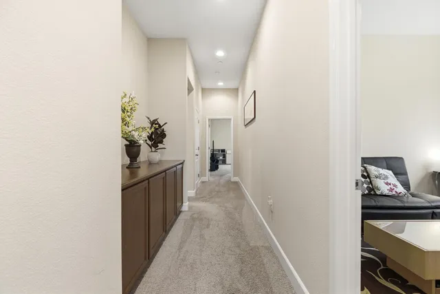 a hallway with a dining table a chandelier and a living room view
