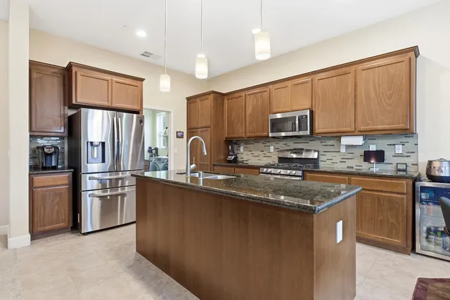 a kitchen with stainless steel appliances granite countertop a stove a sink dishwasher a refrigerator and a microwave oven with cabinets