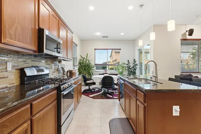 a kitchen with stainless steel appliances granite countertop a stove top oven a sink a counter space and cabinets