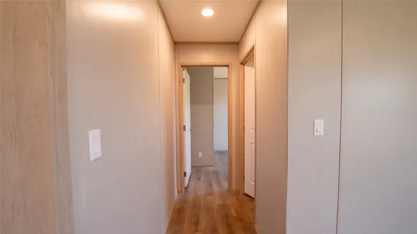a view of hallway with window and wooden floor