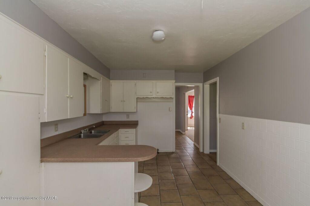 4308 South Travis Street Amarillo, TX 79110 - Photo 9 of 32 a kitchen with a sink a refrigerator and cabinets