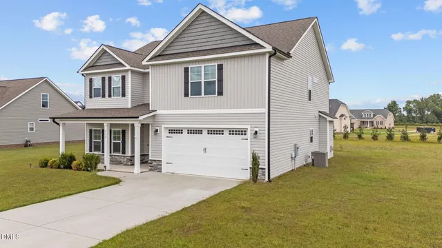 a view of a white house next to a yard with potted plants