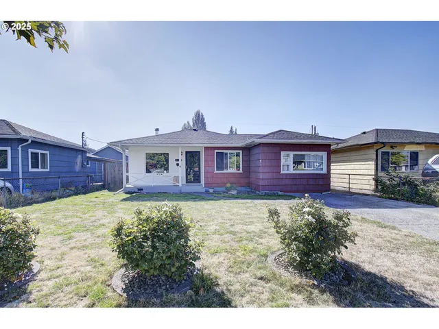 a view of a yard in front of a house with large windows