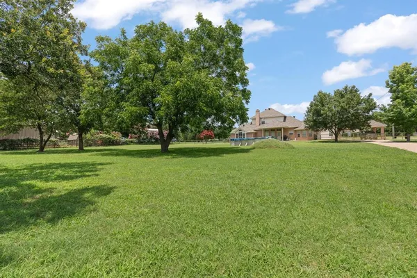 a view of grassy field with benches and trees all around