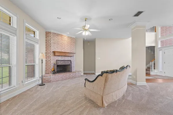 a view of an empty room with chandelier fan and fire place