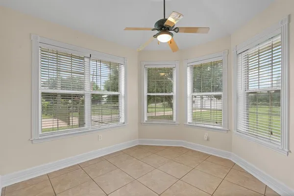 an empty room with chandelier fan and windows