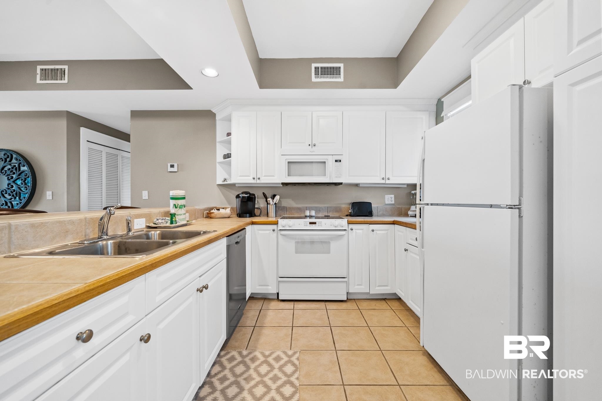815 Plantation Road, Unit 405 Gulf Shores, AL 36542 - Photo 6 of 39 Kitchen featuring sink, white appliances, white cabinets, and light tile patterned flooring