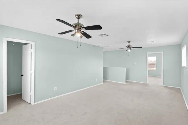 an empty room with windows and fan