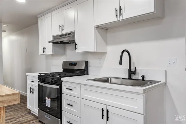 a kitchen with stainless steel appliances granite countertop a stove and a white wooden cabinets