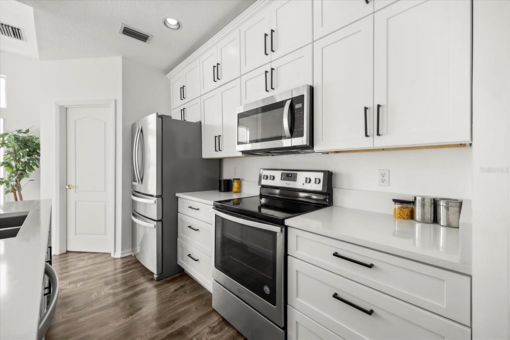 220 Wimbledon Circle Lake Mary, FL 32746 - Photo 13 of 38 a kitchen with stainless steel appliances white cabinets white stove a refrigerator and a microwave