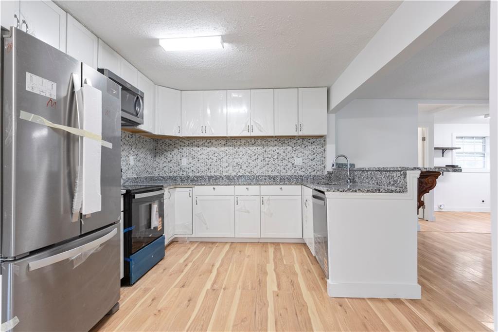 4361 Ben Hill Road Lithia Springs, GA 30122 - Photo 14 of 35 a kitchen with kitchen island granite countertop a refrigerator oven a sink dishwasher and white cabinets with wooden floor