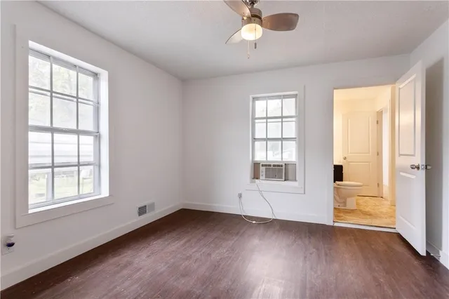 an empty room with wooden floor cabinet and windows