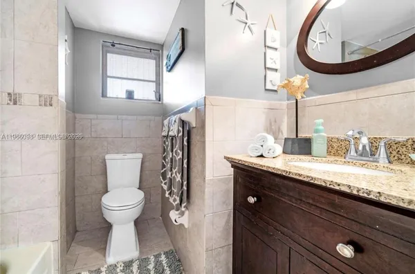 a bathroom with a granite countertop toilet sink and mirror